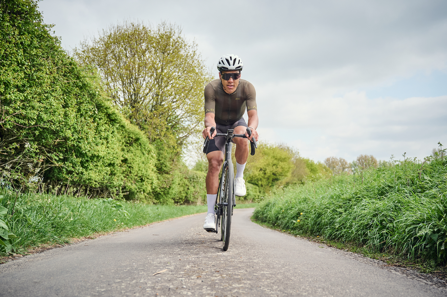 Male cyclist on hedge-lined country lane